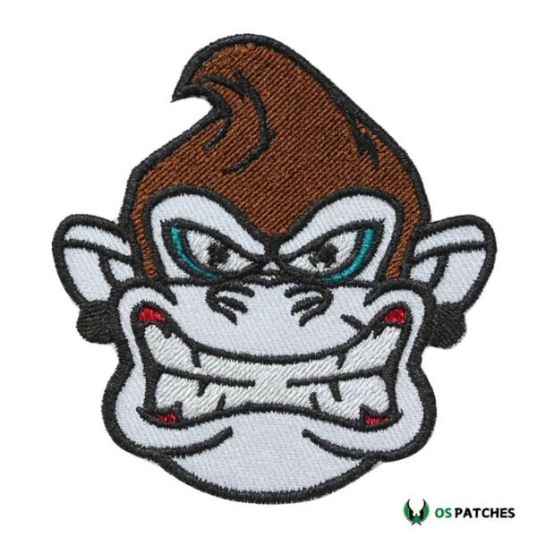 Embroidered iron on angry monkey face patch with sharp teeth and fierce expression.