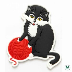 Black and white PVC cat patch holding a red yarn ball